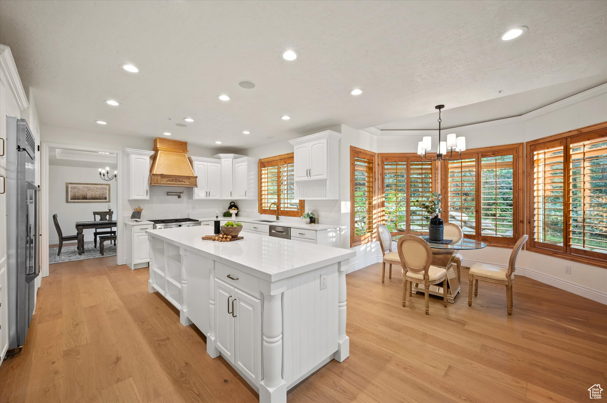 Kitchen with plenty of natural light, custom range hood, white cabinets, and a kitchen island