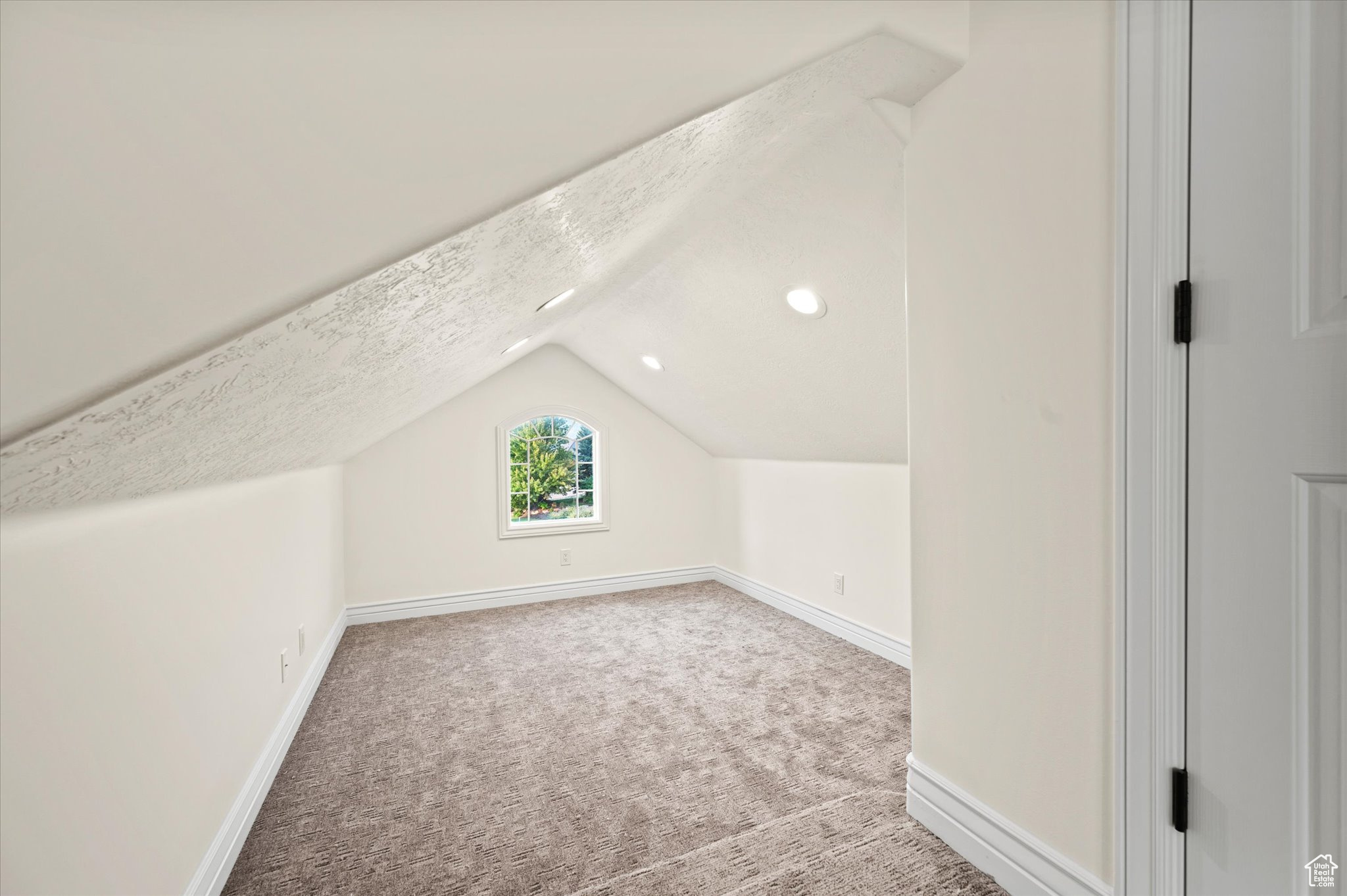 Additional living space featuring carpet floors, a textured ceiling, and vaulted ceiling