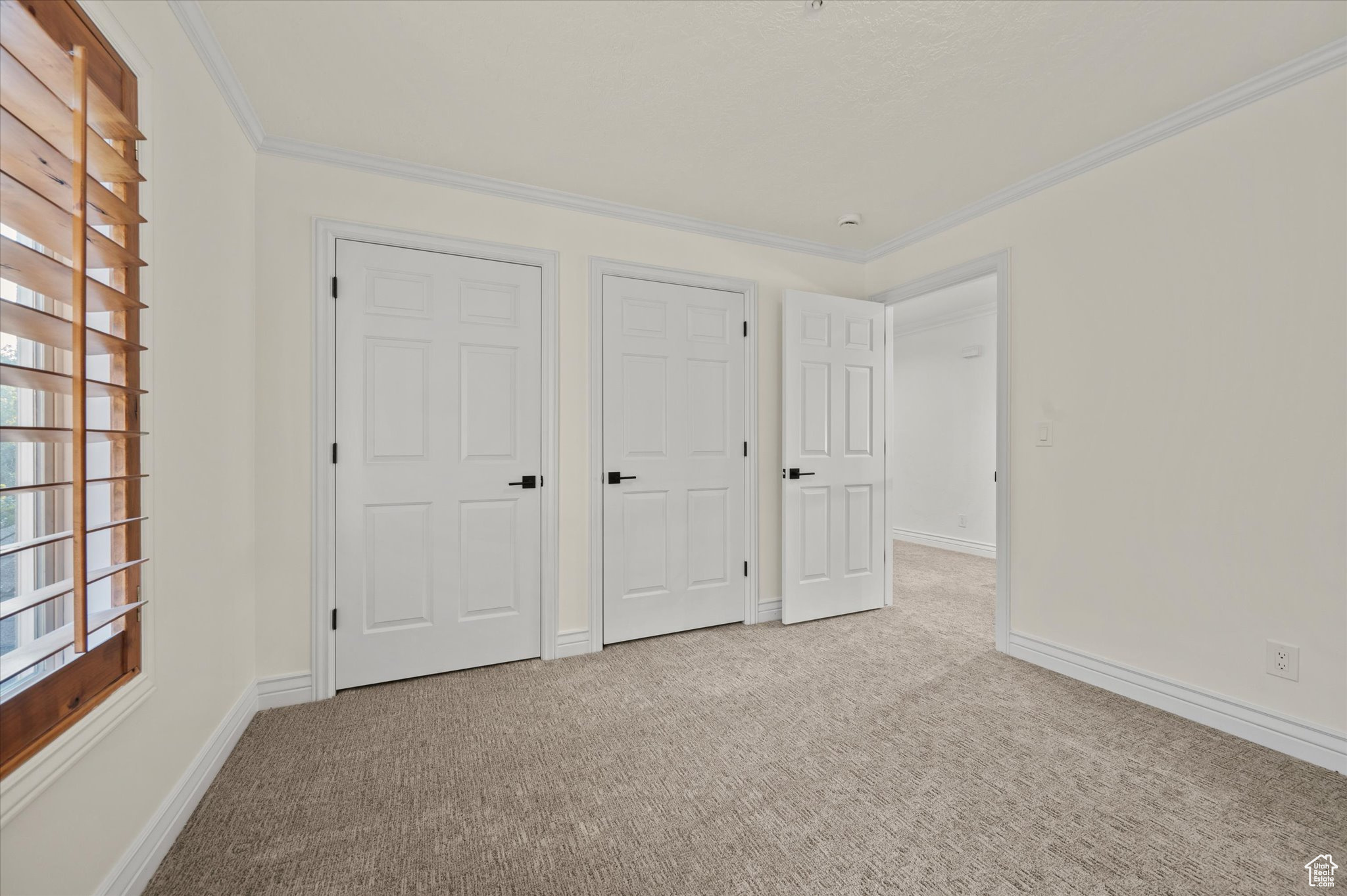 Unfurnished bedroom with crown molding and light colored carpet