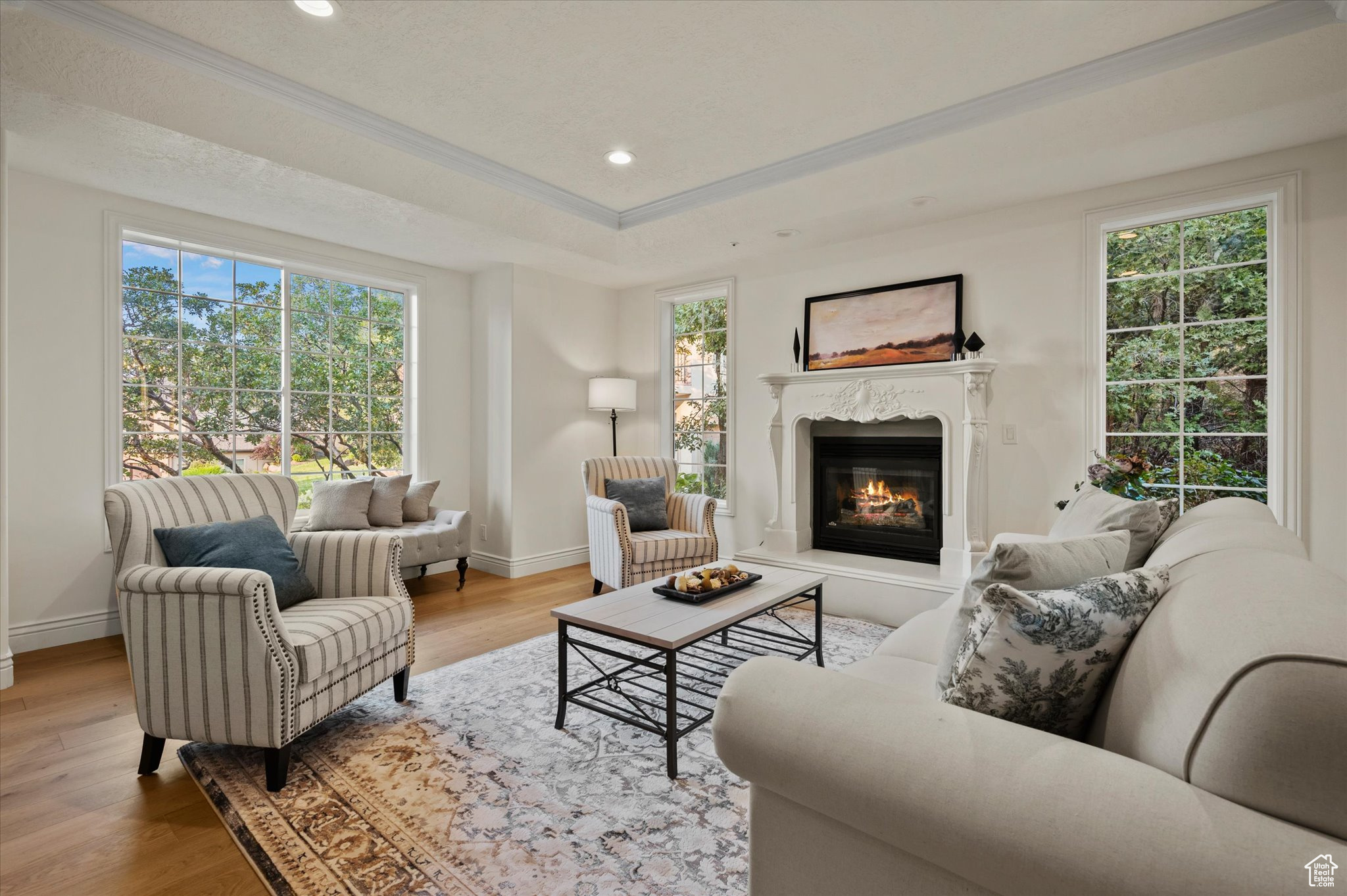 Living room featuring hardwood / wood-style flooring, plenty of natural light, a high end fireplace, and ornamental molding