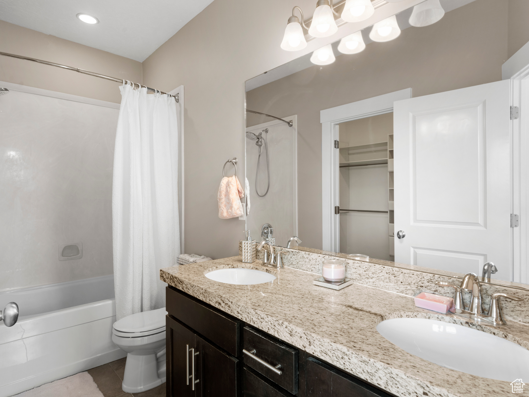 Ensuite bathroom featuring double vanity, toilet, shower / tub combo, and tile  floors