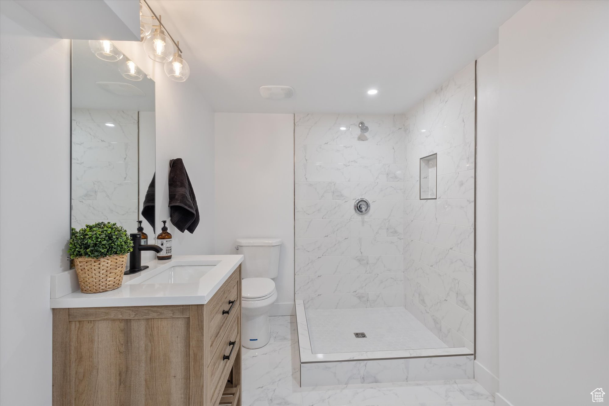 Bathroom featuring vanity, toilet, and a tile shower