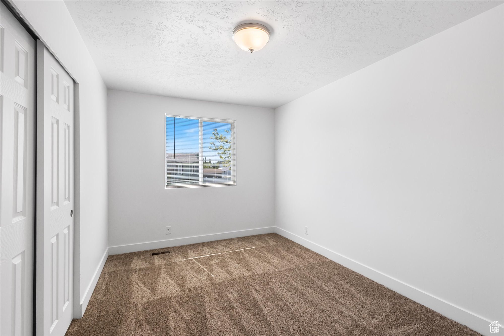 Unfurnished bedroom with a closet, a textured ceiling, and carpet flooring