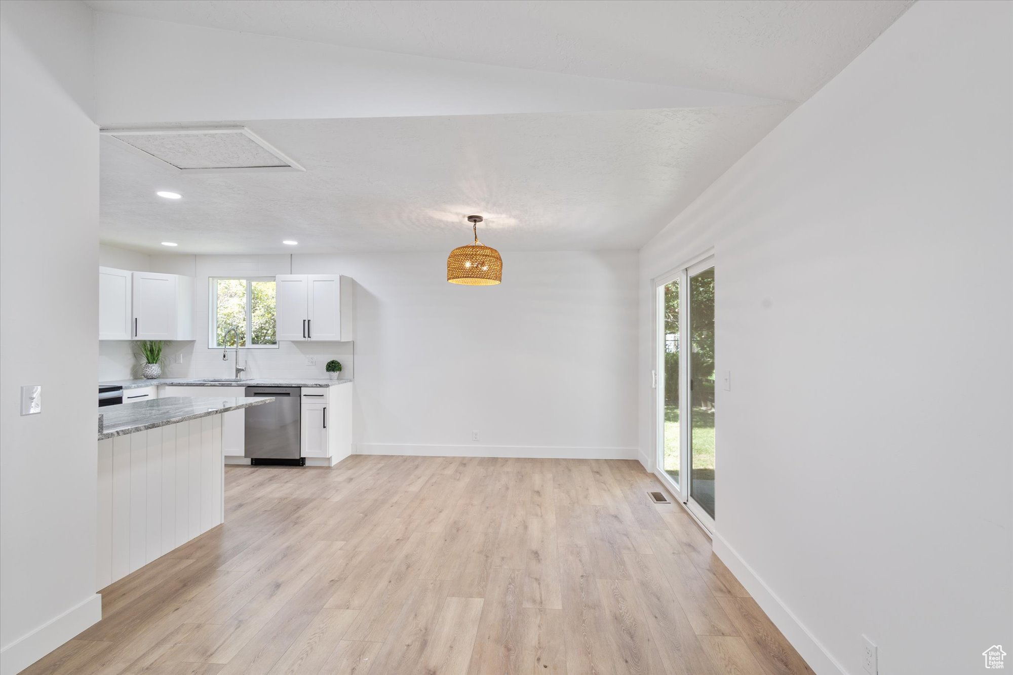 Kitchen featuring pendant lighting, white cabinetry, dishwasher, sink, and light hardwood / wood-style floors