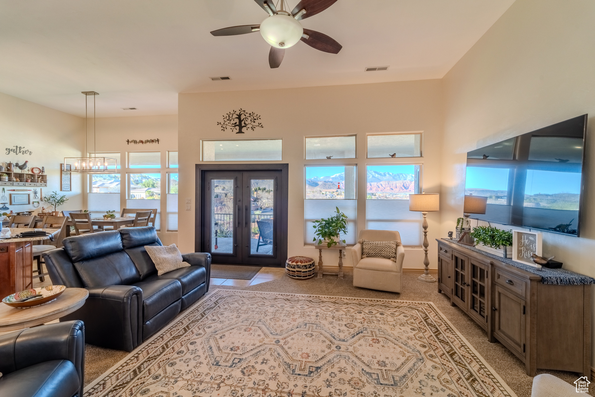 Living room featuring ceiling fan with notable chandelier and plenty of natural light