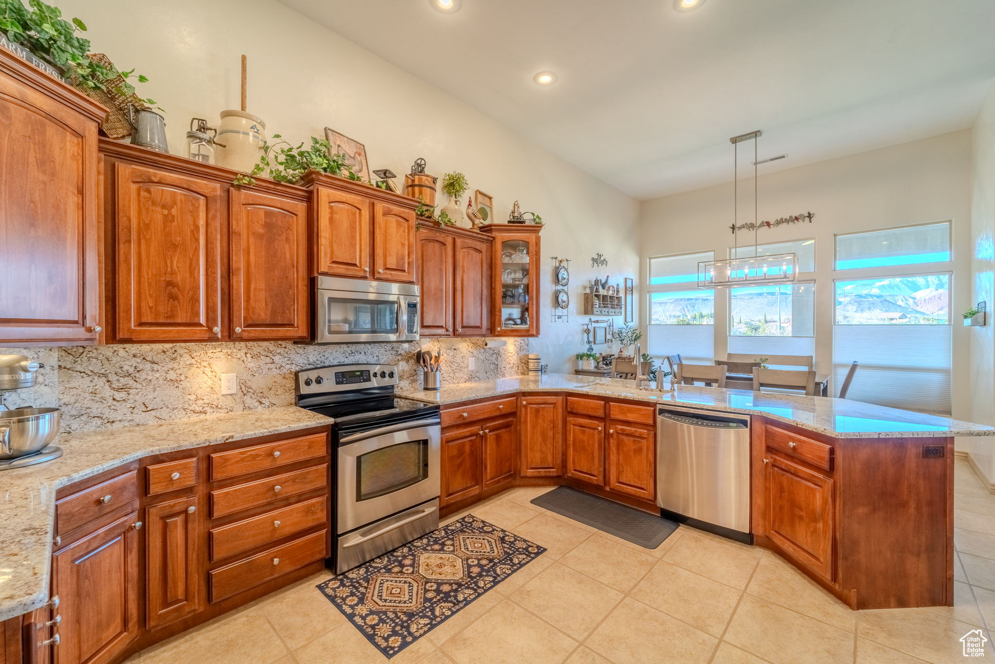 Kitchen featuring pendant lighting, light stone counters, stainless steel appliances, and tasteful backsplash