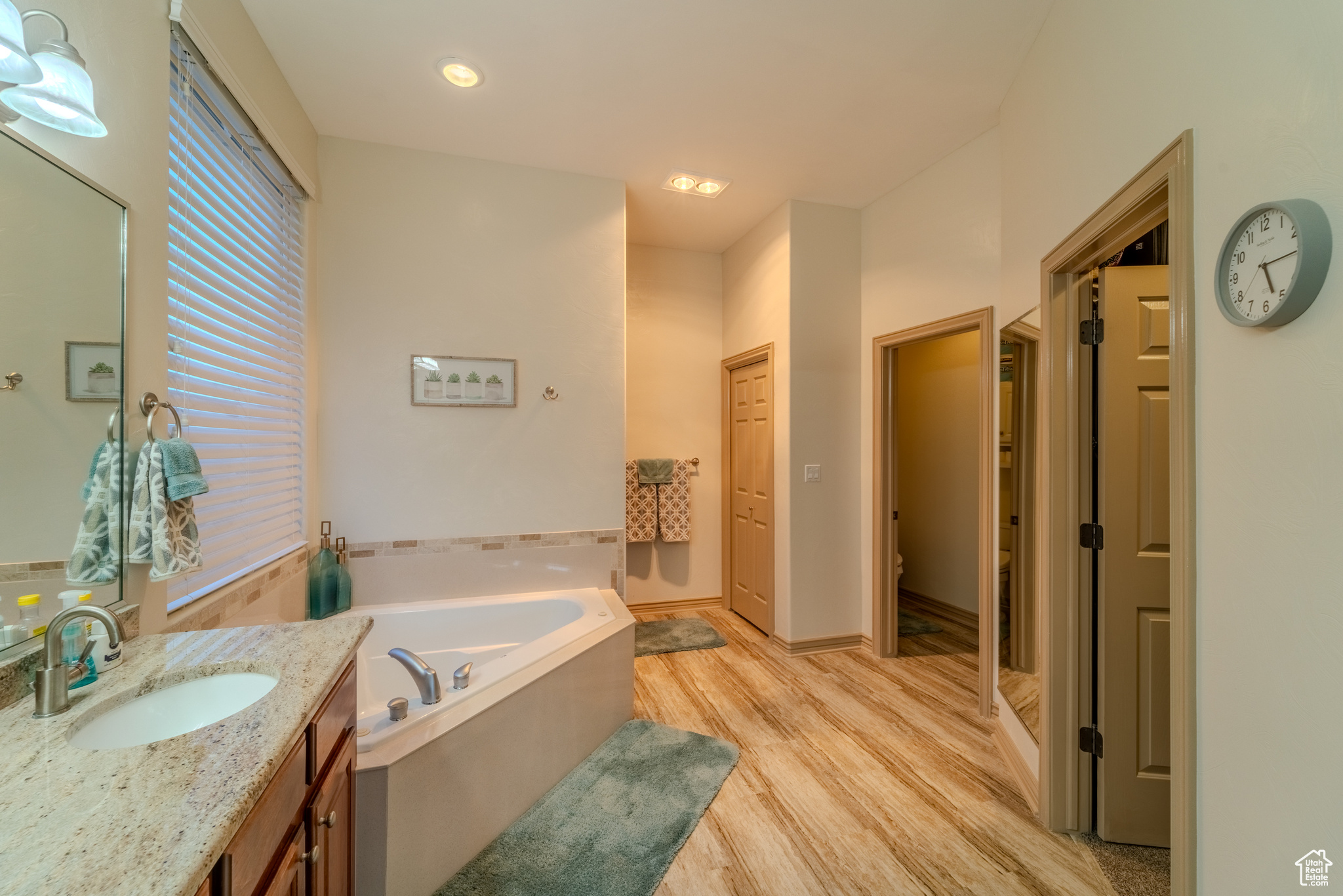 Bathroom with a tub to relax in, vanity, toilet, and hardwood / wood-style flooring