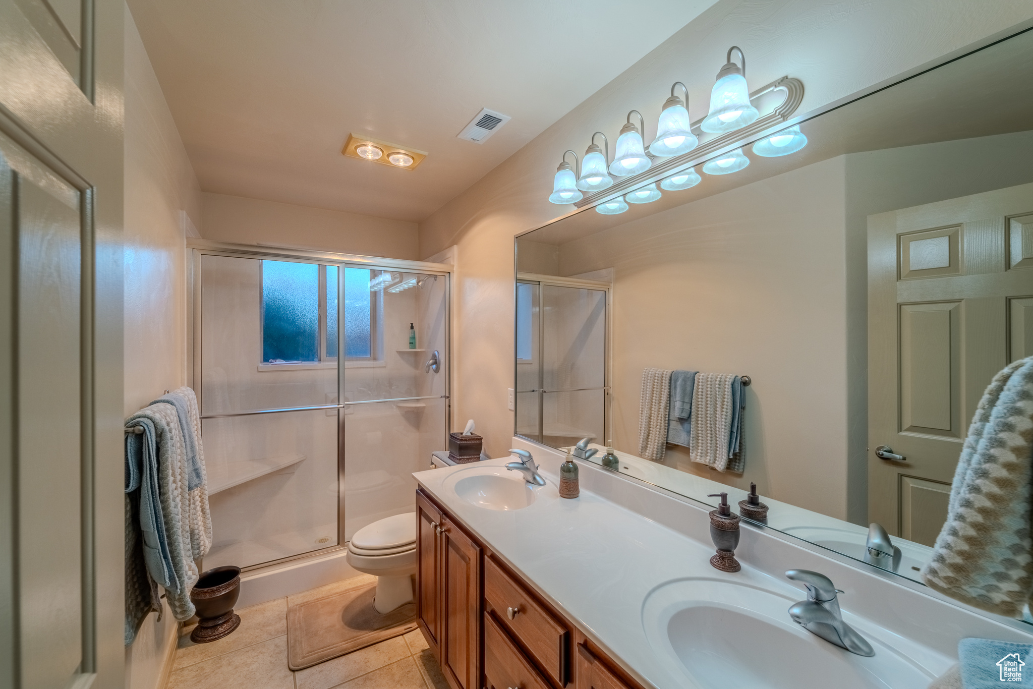 Bathroom with vanity, toilet, walk in shower, and tile patterned flooring