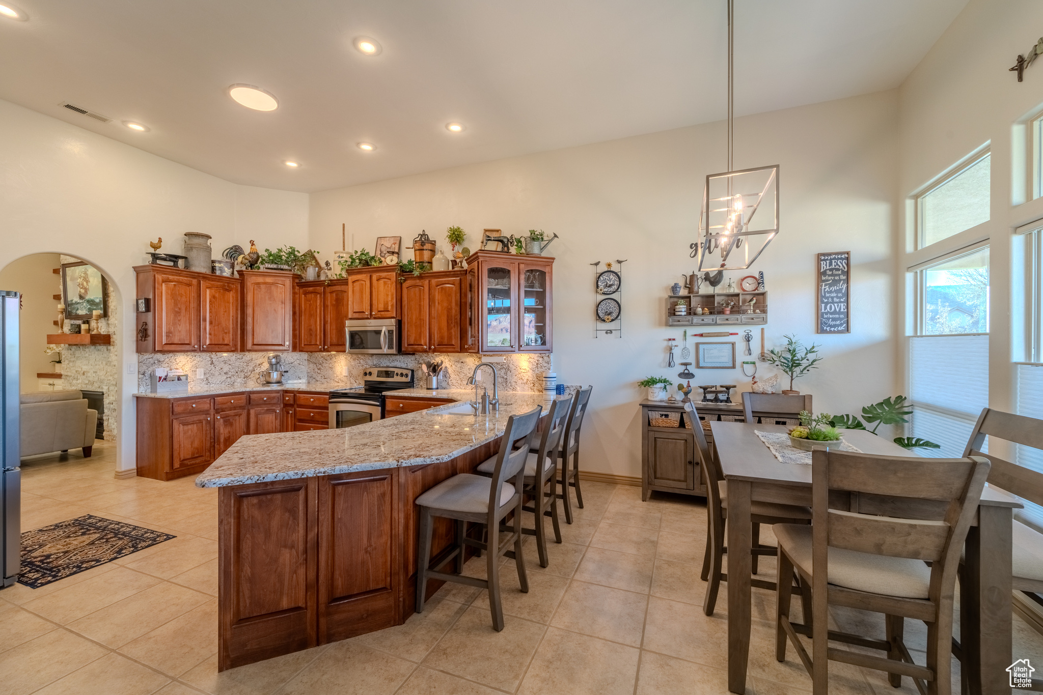 Kitchen with backsplash, light stone counters, appliances with stainless steel finishes, and light tile patterned flooring