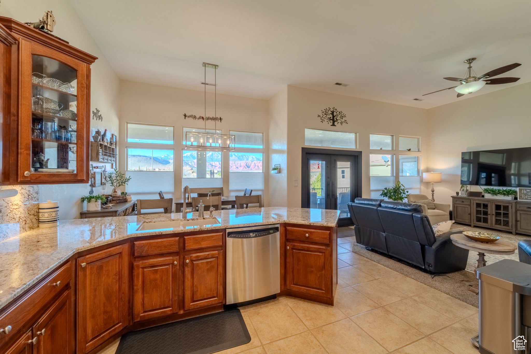 Kitchen featuring ceiling fan with notable chandelier, light tile patterned floors, stainless steel dishwasher, kitchen peninsula, and sink