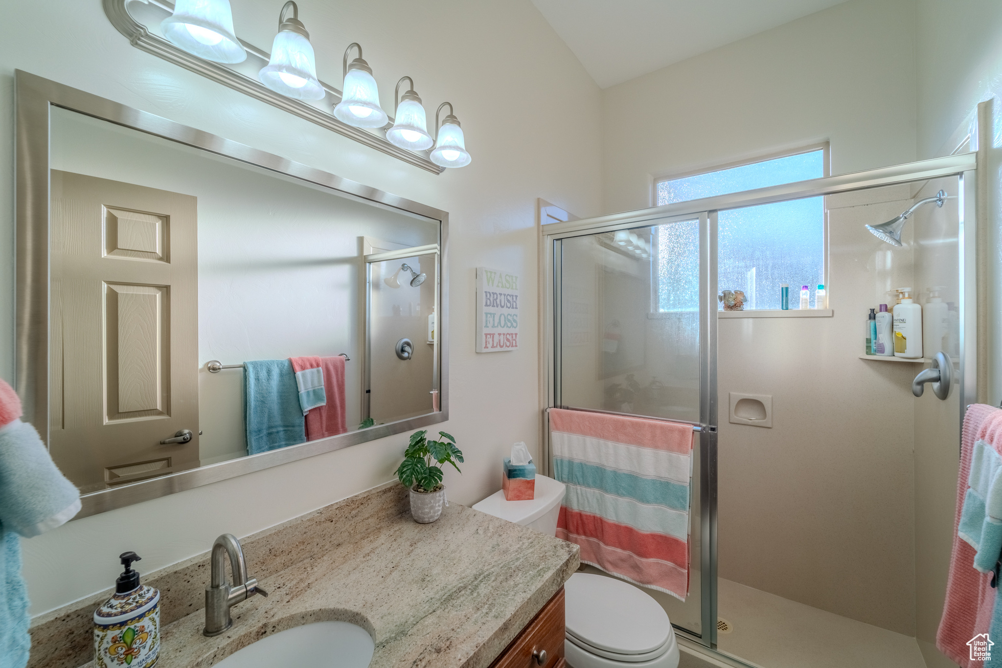 Bathroom featuring vanity, toilet, and an enclosed shower