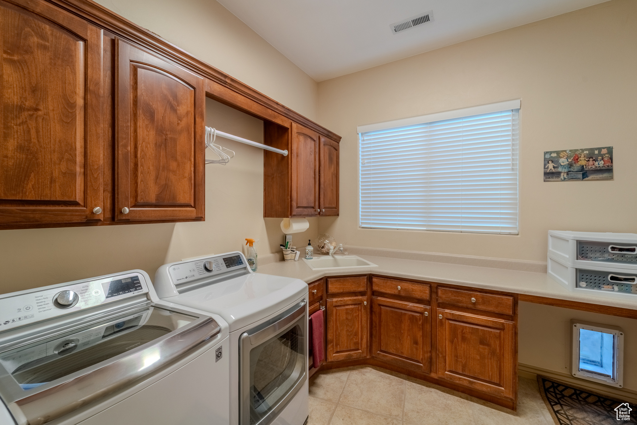 Laundry area featuring separate washer and dryer, cabinets, sink, and light tile patterned flooring