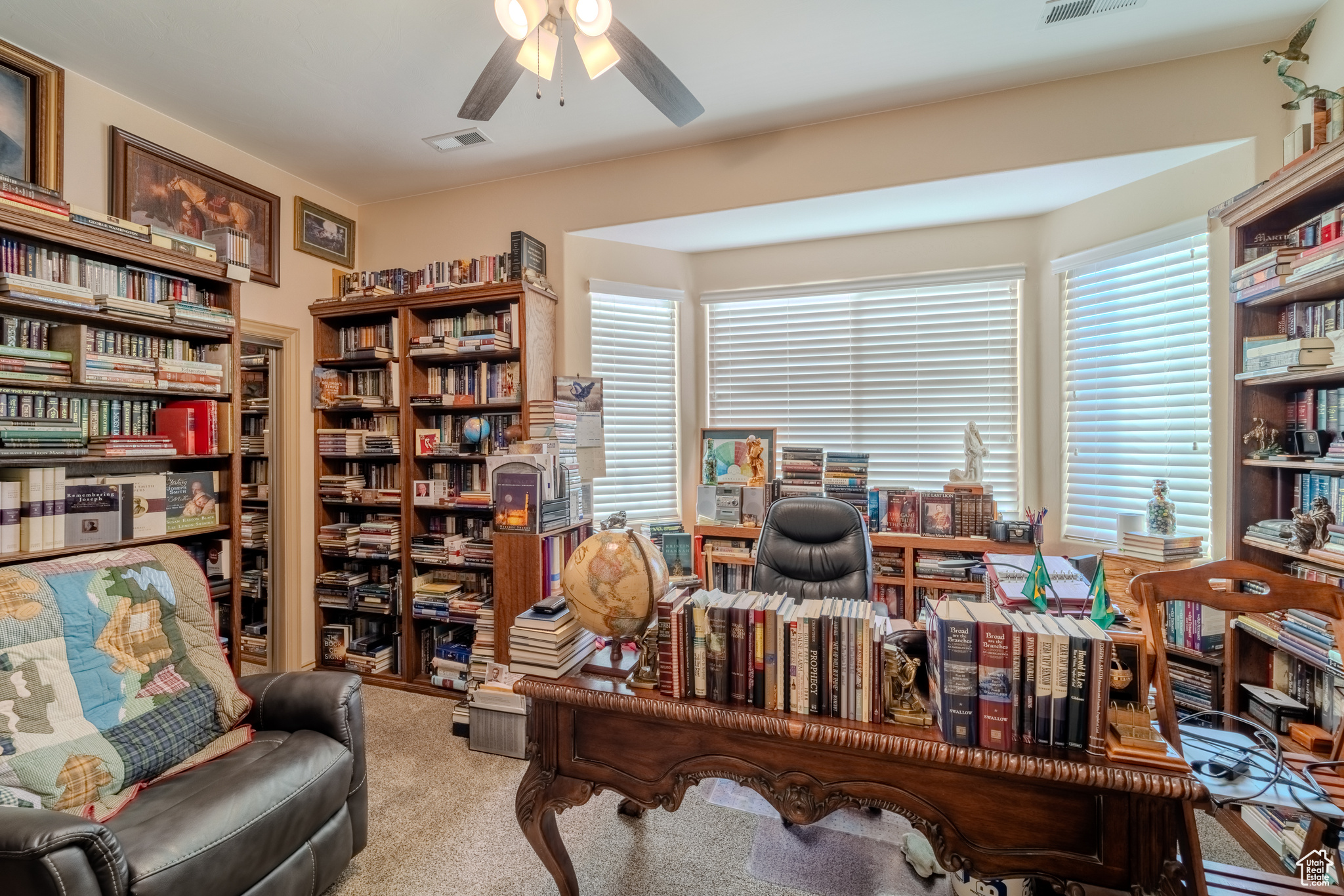 Carpeted office with plenty of natural light and ceiling fan