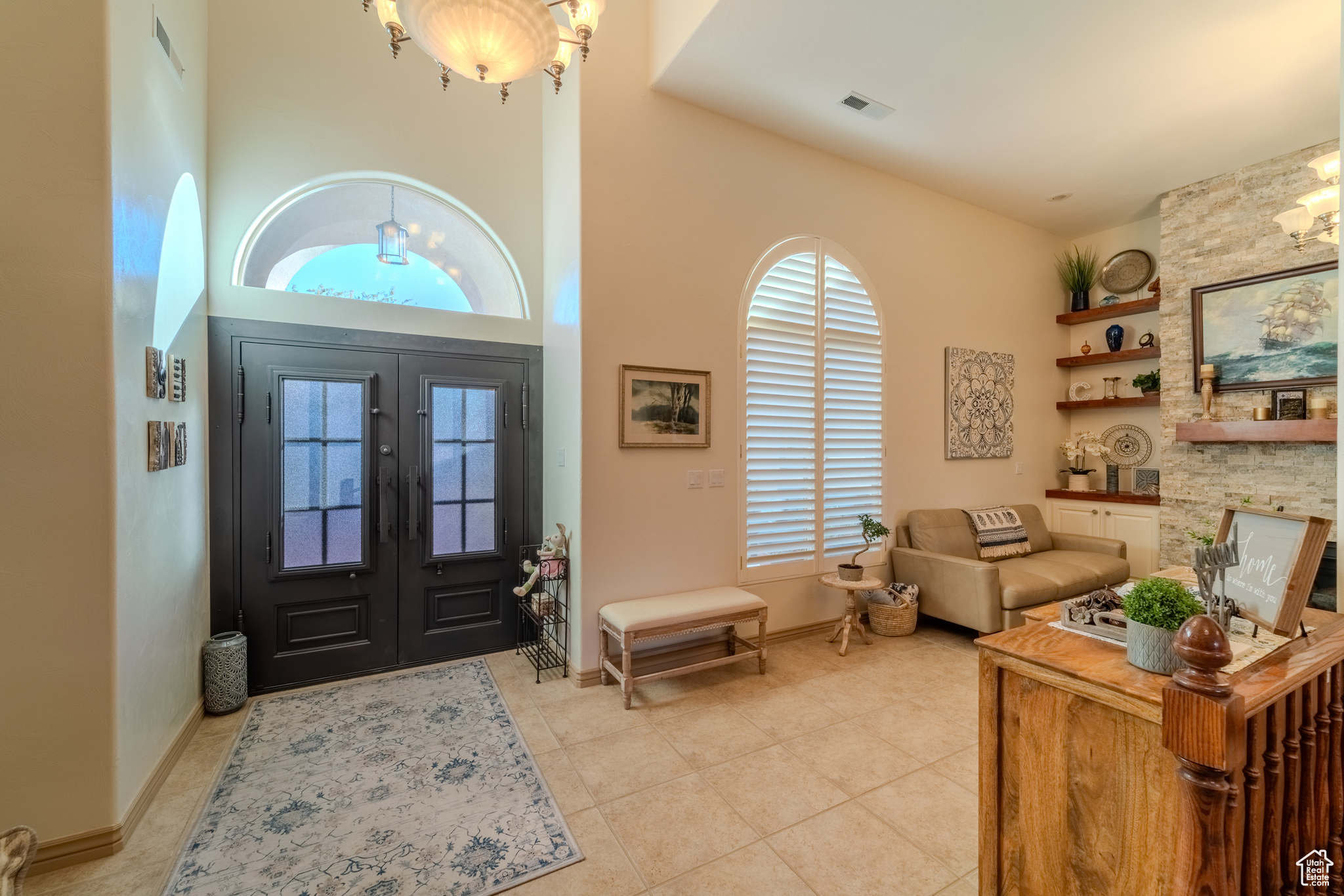 Tiled foyer entrance featuring a towering ceiling, a notable chandelier, and french doors