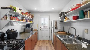 Kitchen with black range, sink, and light hardwood / wood-style flooring