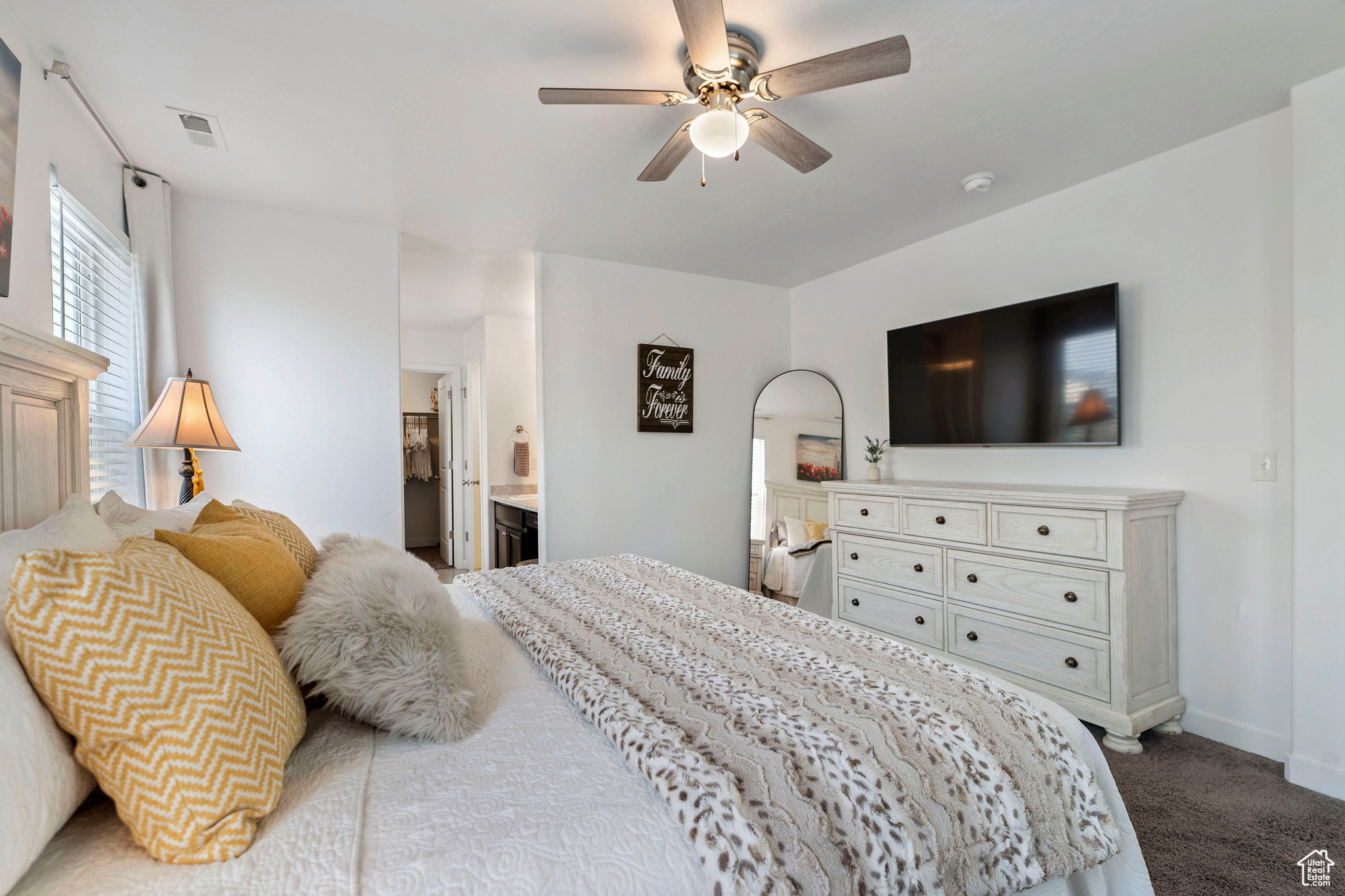 Carpeted bedroom with connected bathroom and ceiling fan