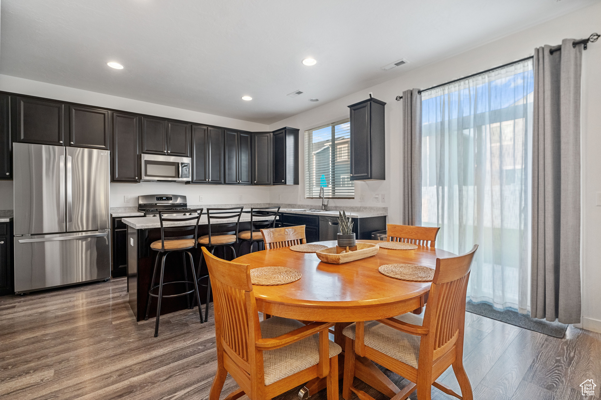 Interior space with appliances with stainless steel finishes, hardwood / wood-style flooring, and a kitchen island