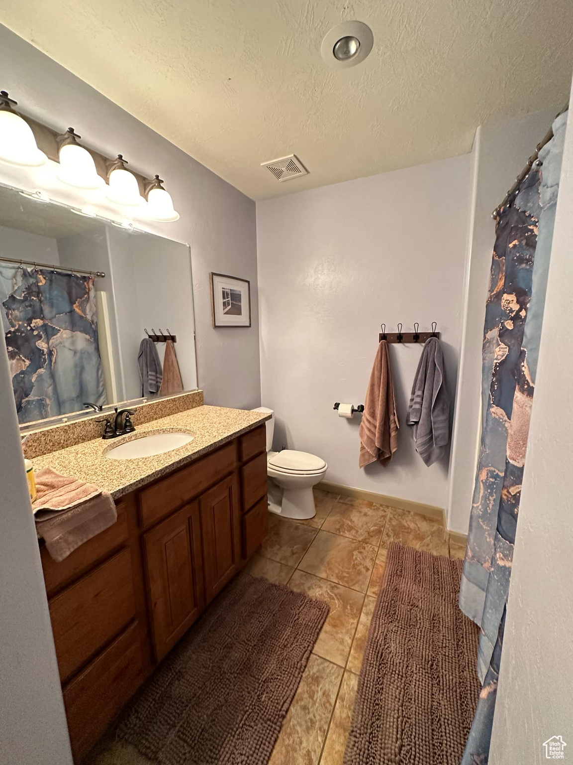 Bathroom with a textured ceiling, vanity, toilet, and tile patterned flooring