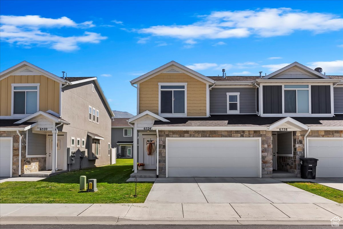 View of front facade featuring a garage and a front lawn