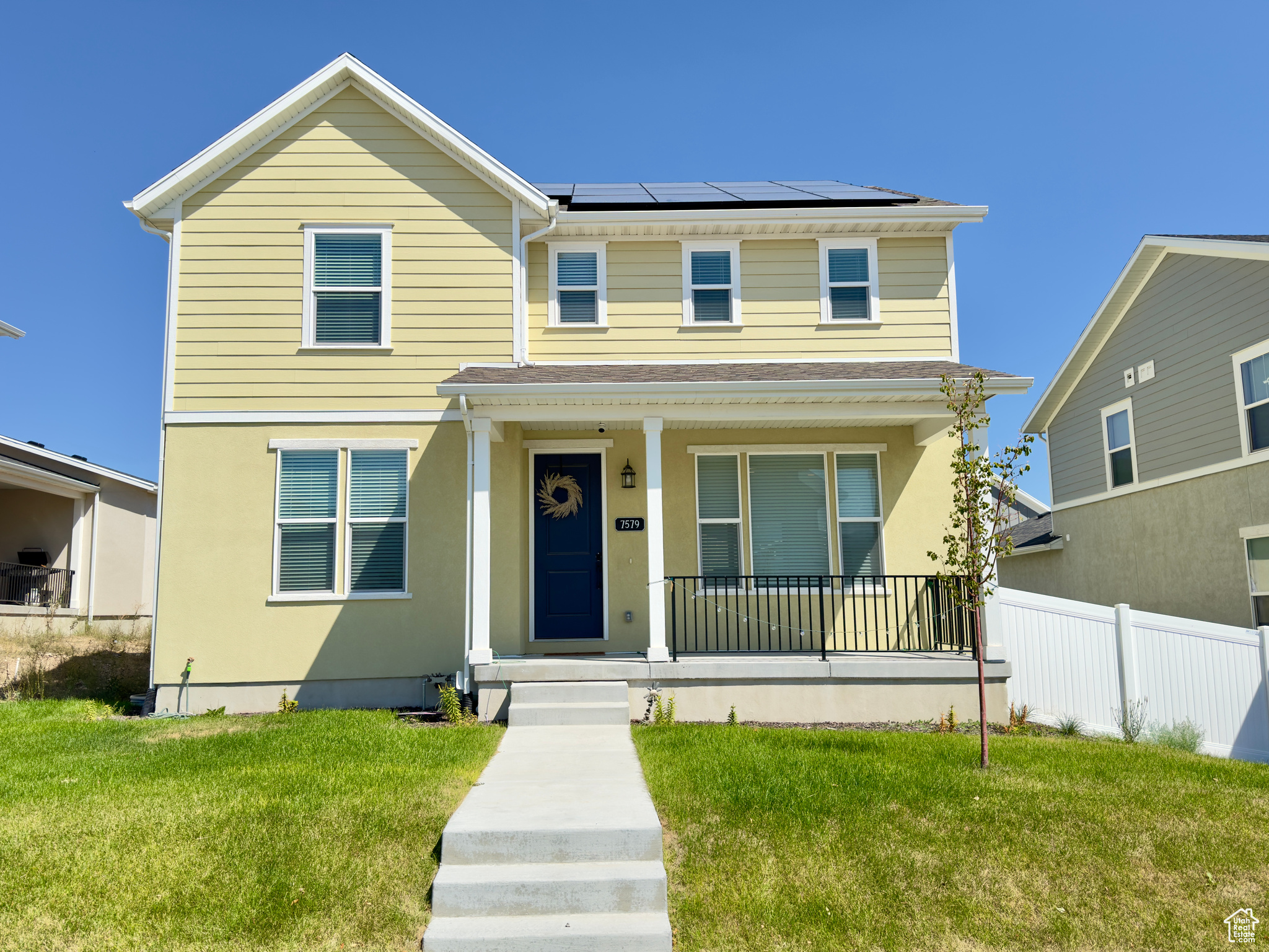 View of front of property featuring a porch, a front lawn, and solar panels