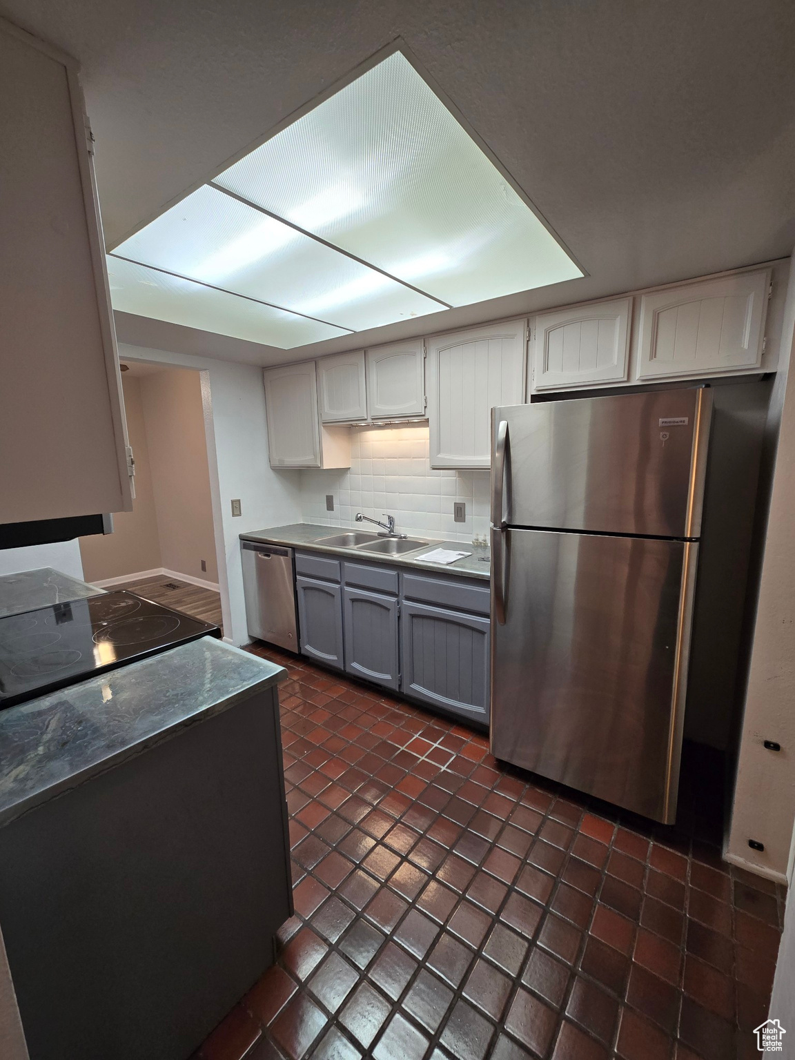 Kitchen with white cabinets, appliances with stainless steel finishes, decorative backsplash, and sink