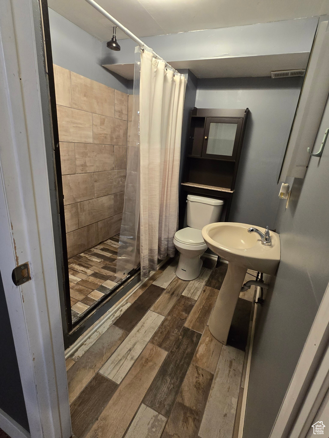 Bathroom featuring hardwood / wood-style floors, toilet, and walk in shower