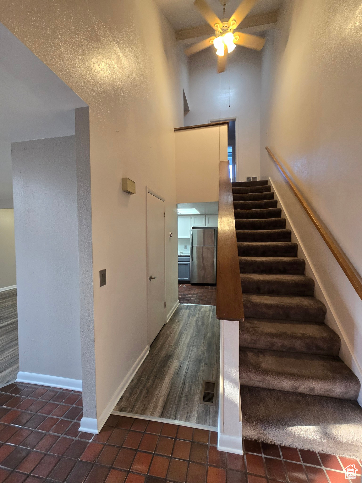 Stairway with hardwood / wood-style floors, ceiling fan, and high vaulted ceiling