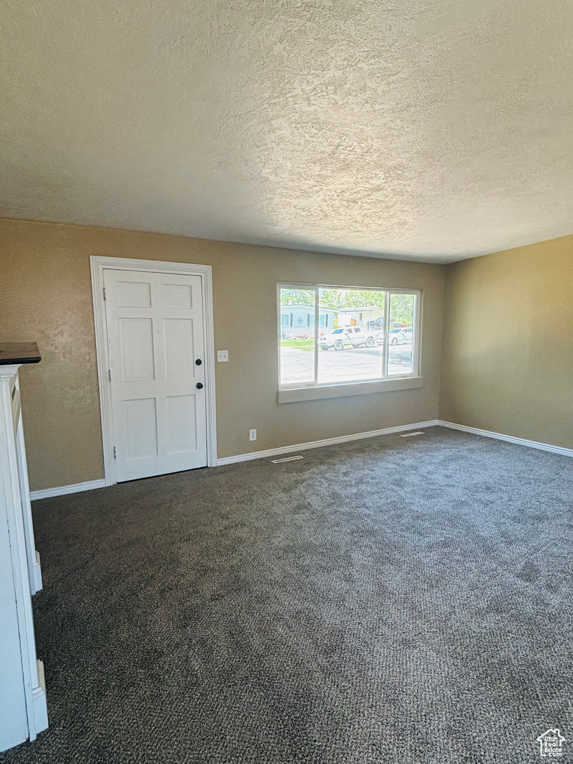 Empty room with a textured ceiling and carpet flooring