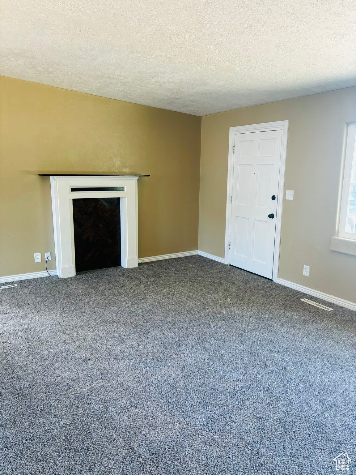 Unfurnished living room with a textured ceiling and carpet