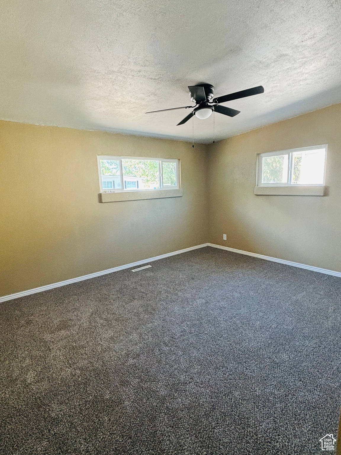 Carpeted spare room featuring ceiling fan and a textured ceiling