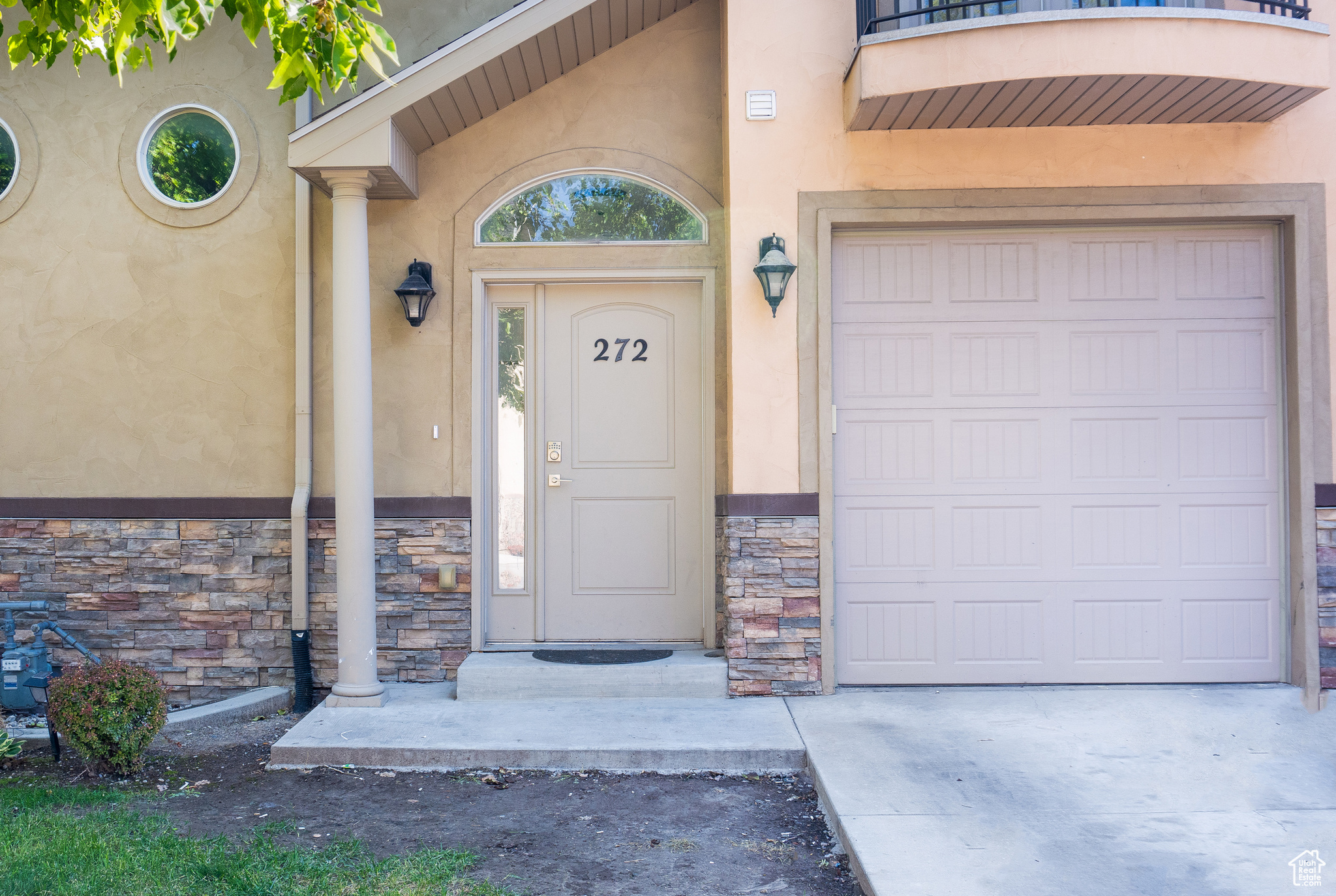 View of exterior entry with a garage and a balcony