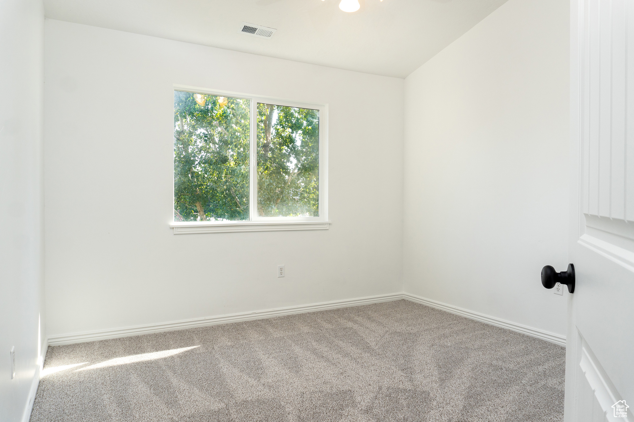 Carpeted spare room with vaulted ceiling