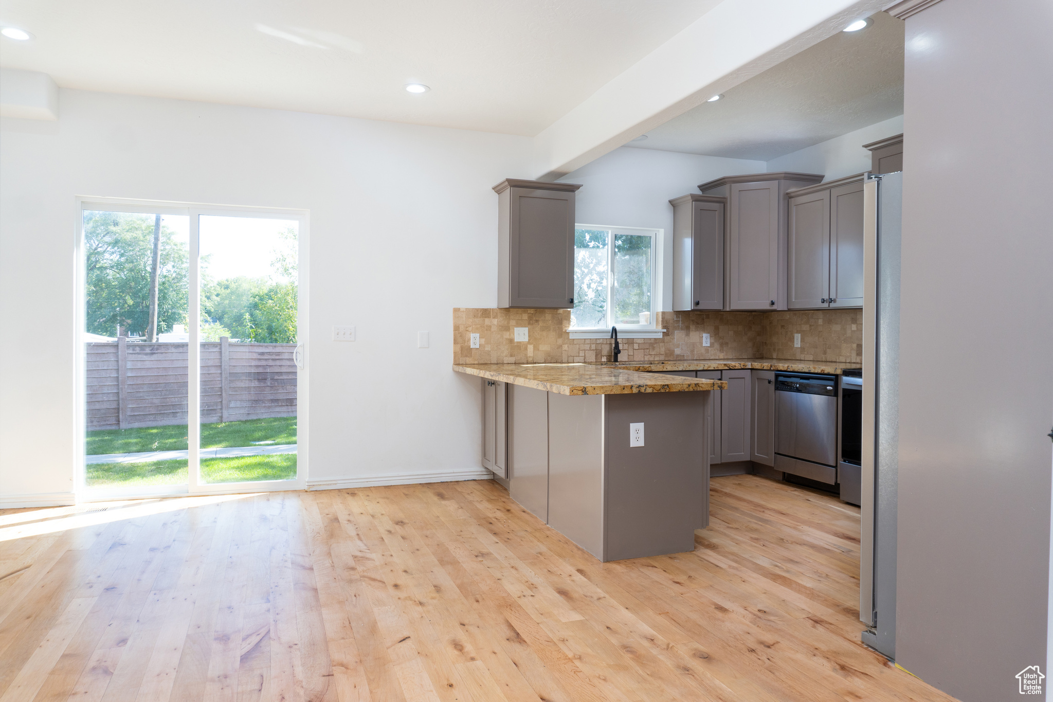 Kitchen featuring plenty of natural light, stainless steel dishwasher, light hardwood / wood-style flooring, and kitchen peninsula