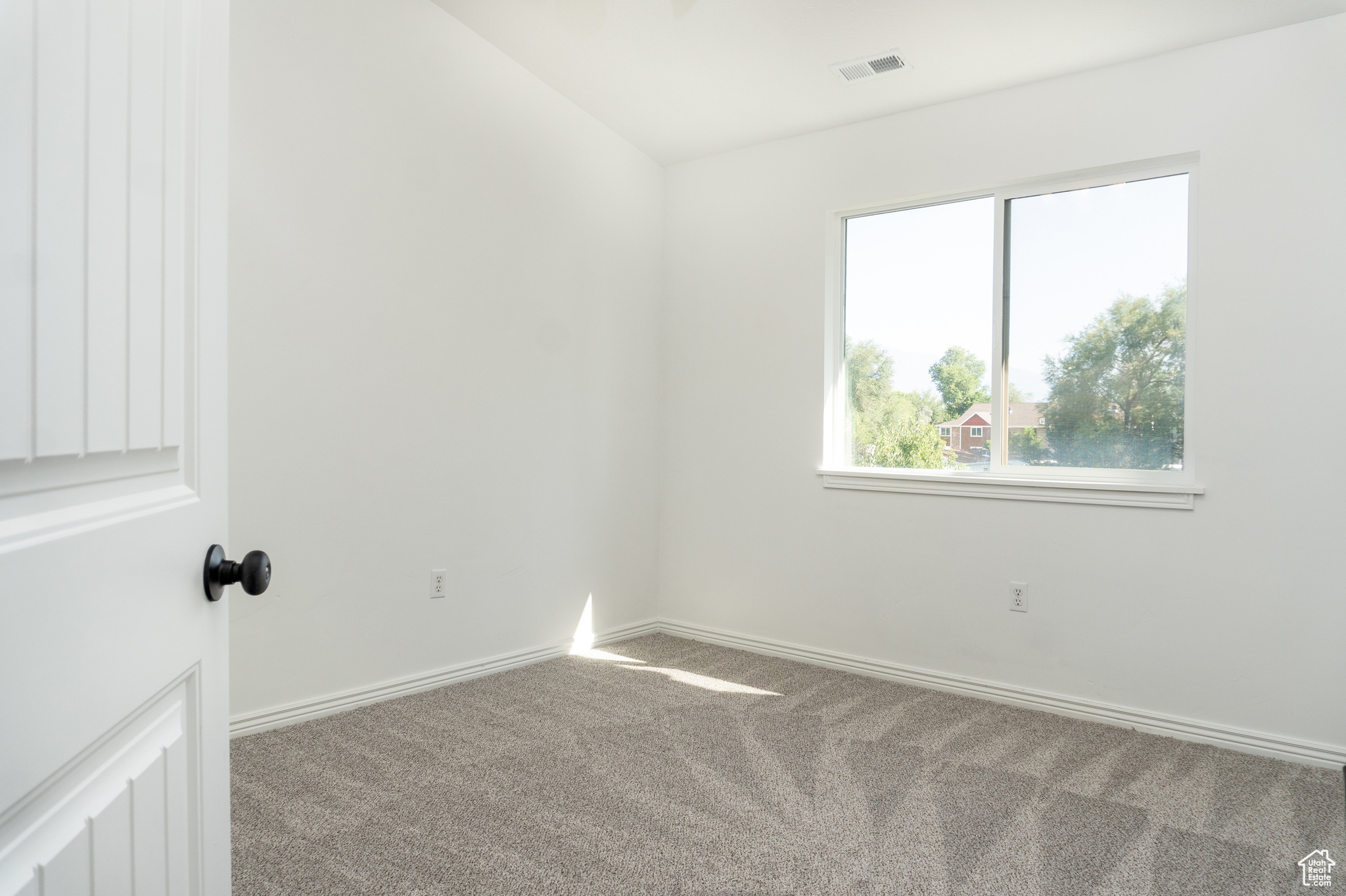 Carpeted empty room with vaulted ceiling