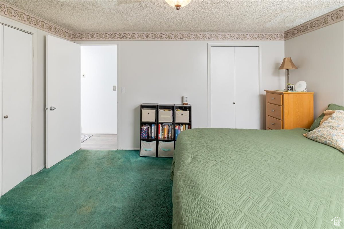 Carpeted bedroom featuring a textured ceiling and two closets