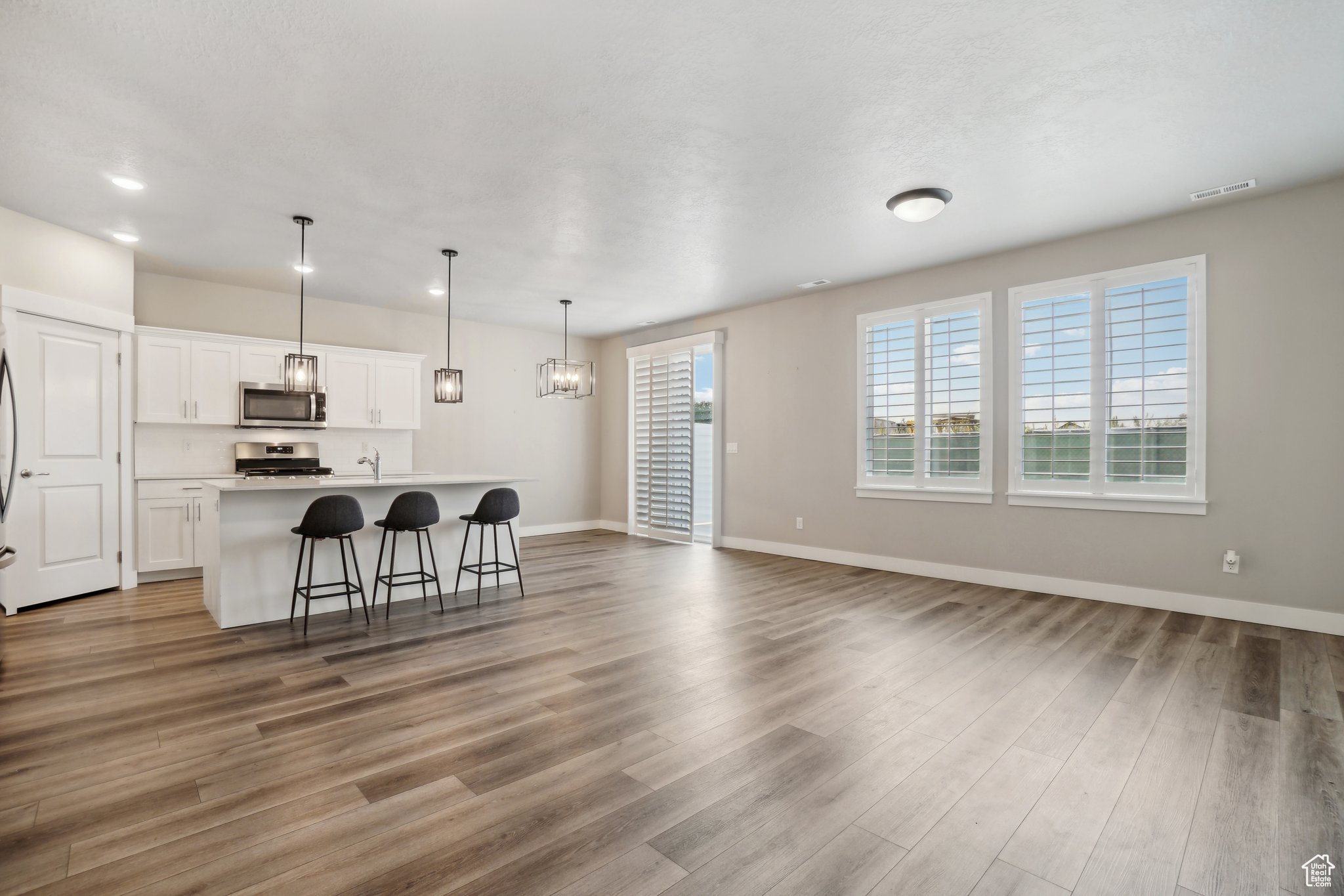 Interior space with a breakfast bar, hardwood / wood-style floors, stainless steel appliances, and a center island with sink