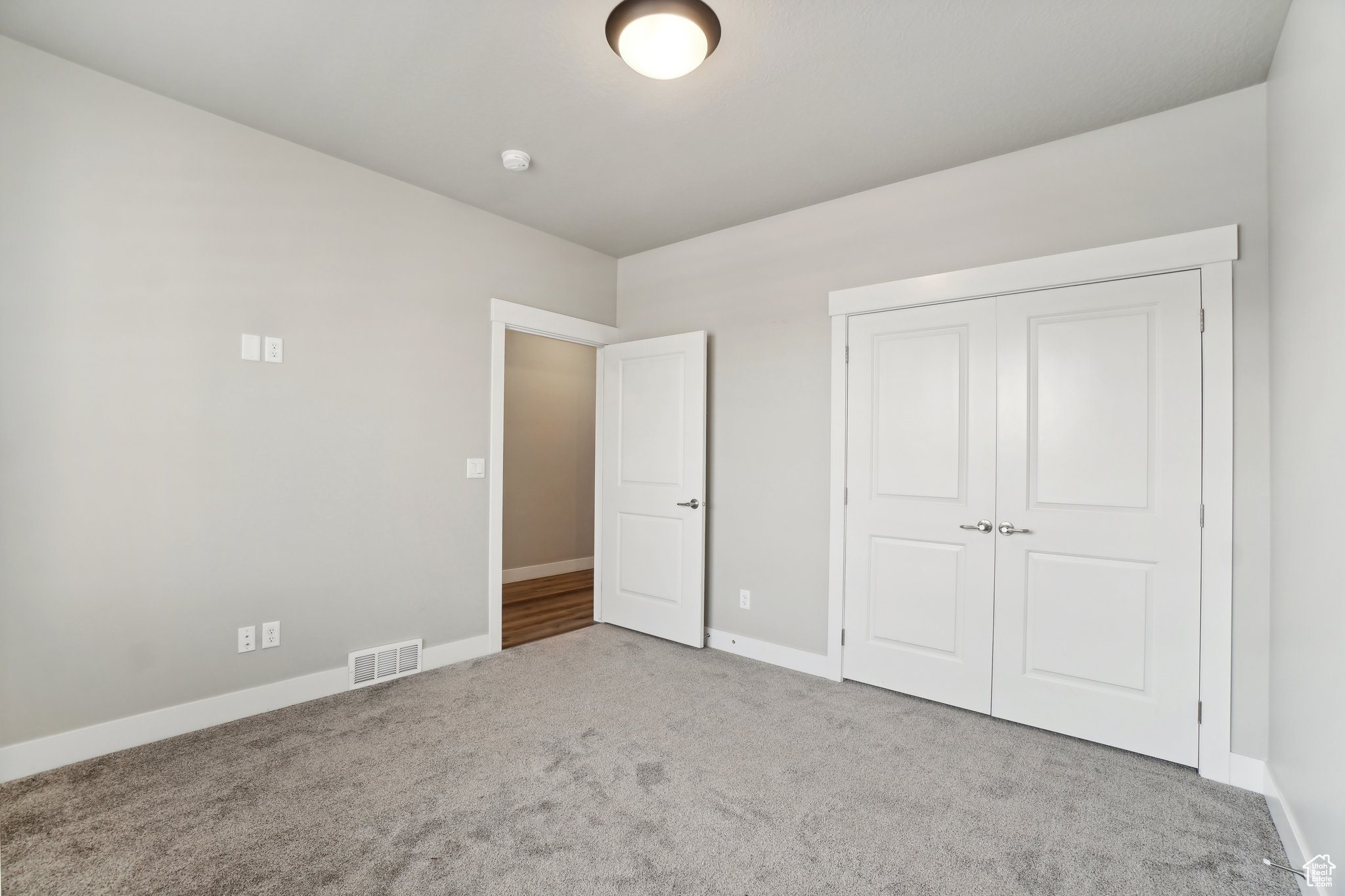 Unfurnished bedroom with light colored carpet and a closet