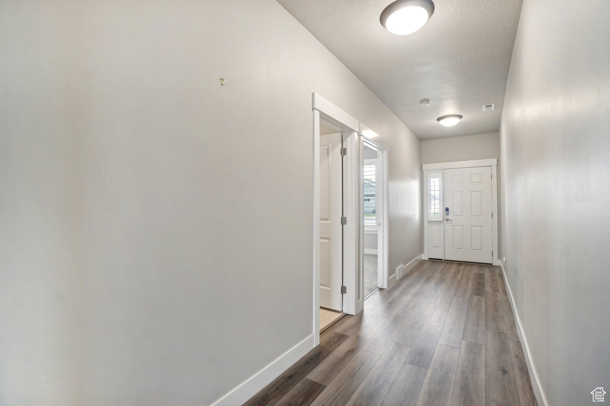 Hall with dark hardwood / wood-style floors and a textured ceiling