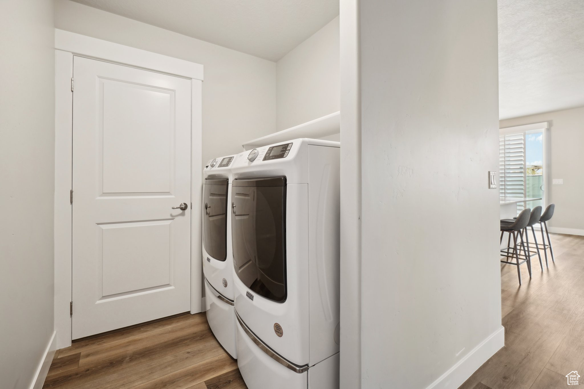 Clothes washing area with independent washer and dryer and light wood-type flooring