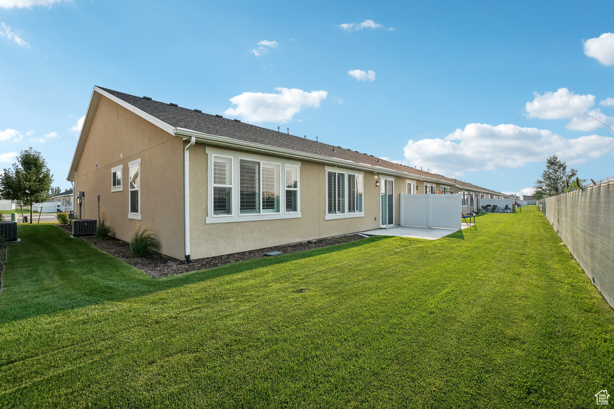 Rear view of property with central AC unit, a patio area, and a lawn