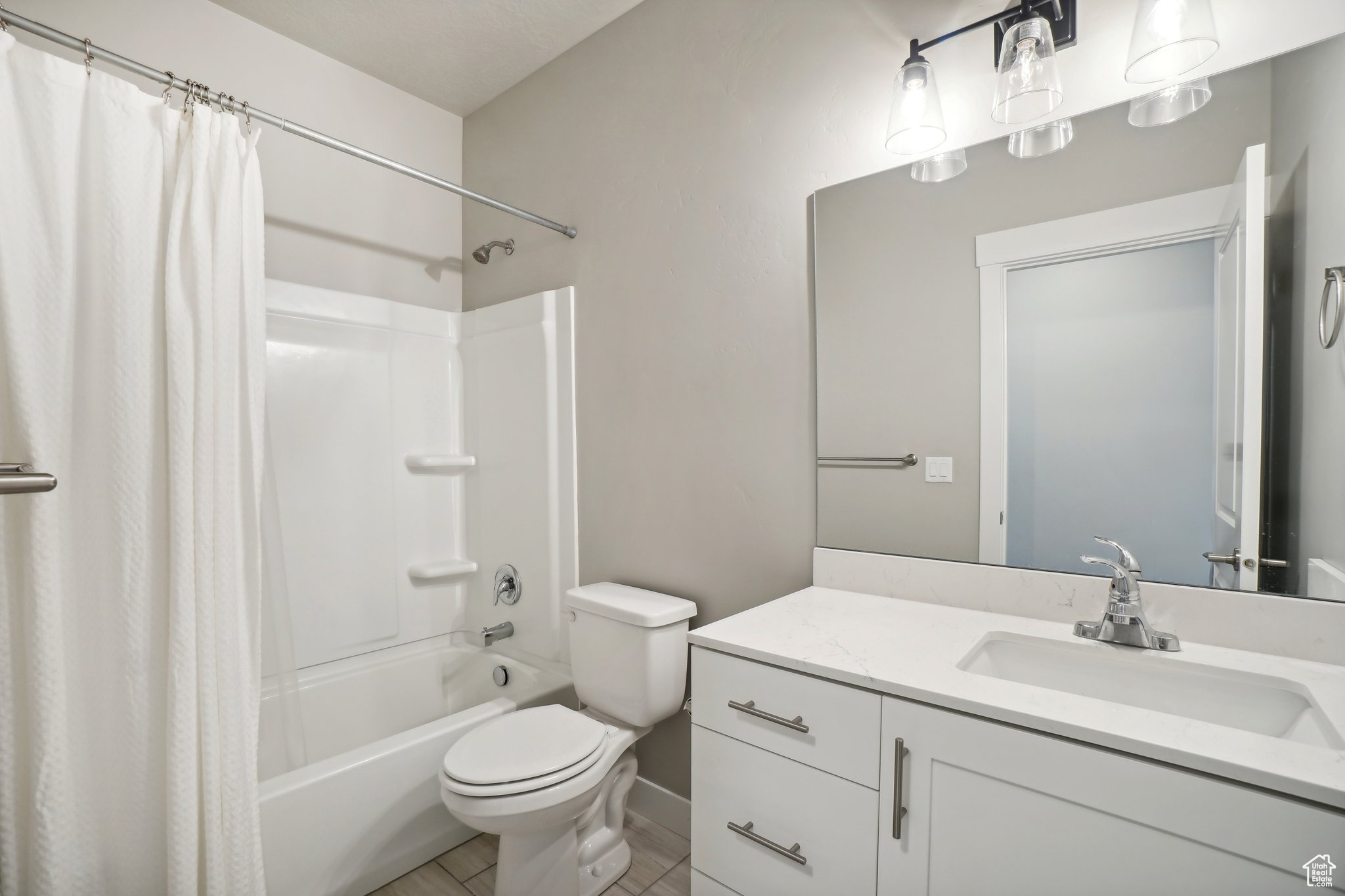 Full bathroom with tile patterned floors, shower / bath combination with curtain, toilet, and vanity