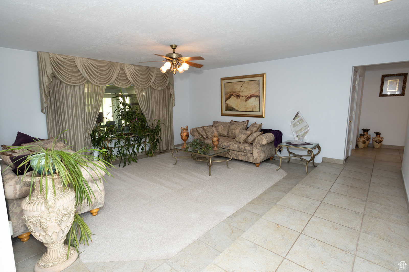 Living room with ceiling fan, a textured ceiling, and light tile patterned flooring