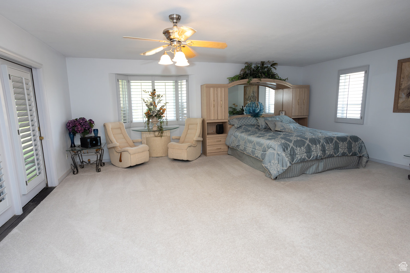 Carpeted bedroom with ceiling fan and multiple windows