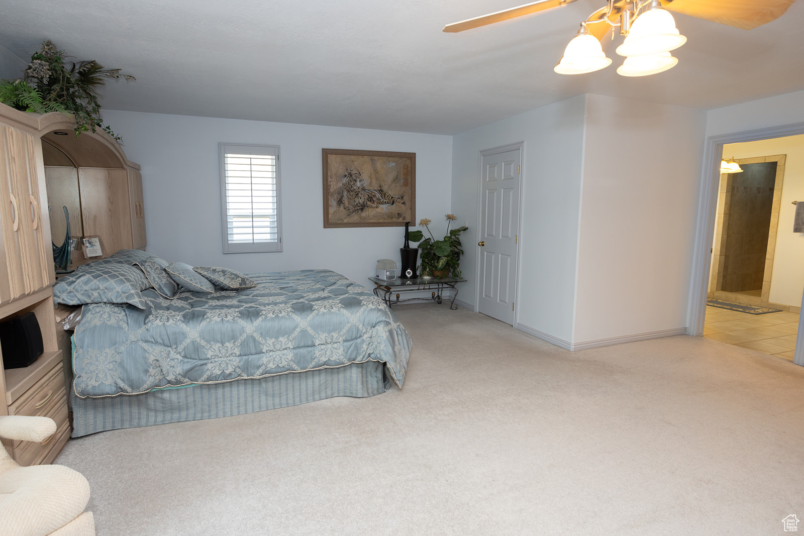 Carpeted bedroom with connected bathroom and ceiling fan