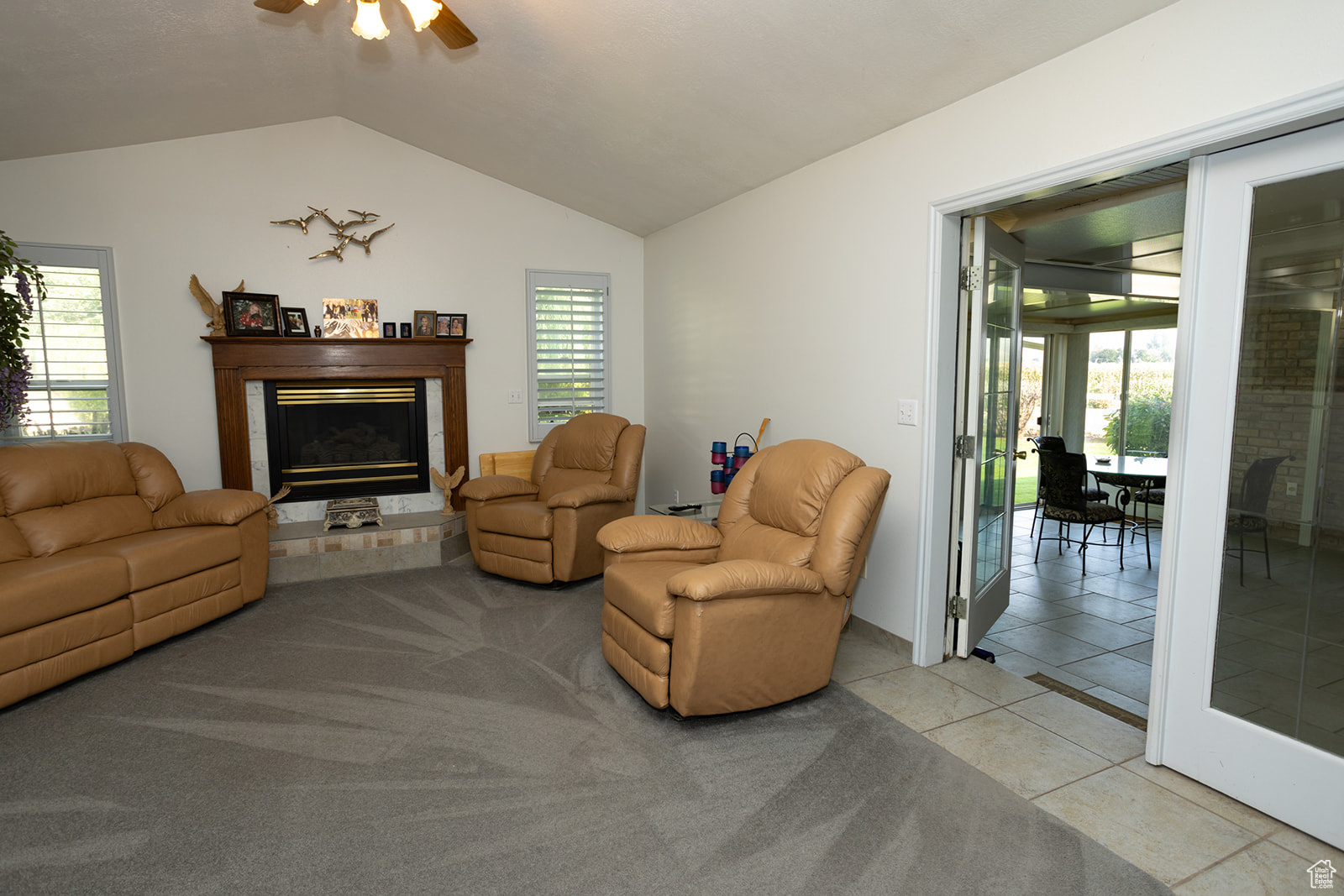 Living room featuring ceiling fan, light tile patterned floors, and vaulted ceiling