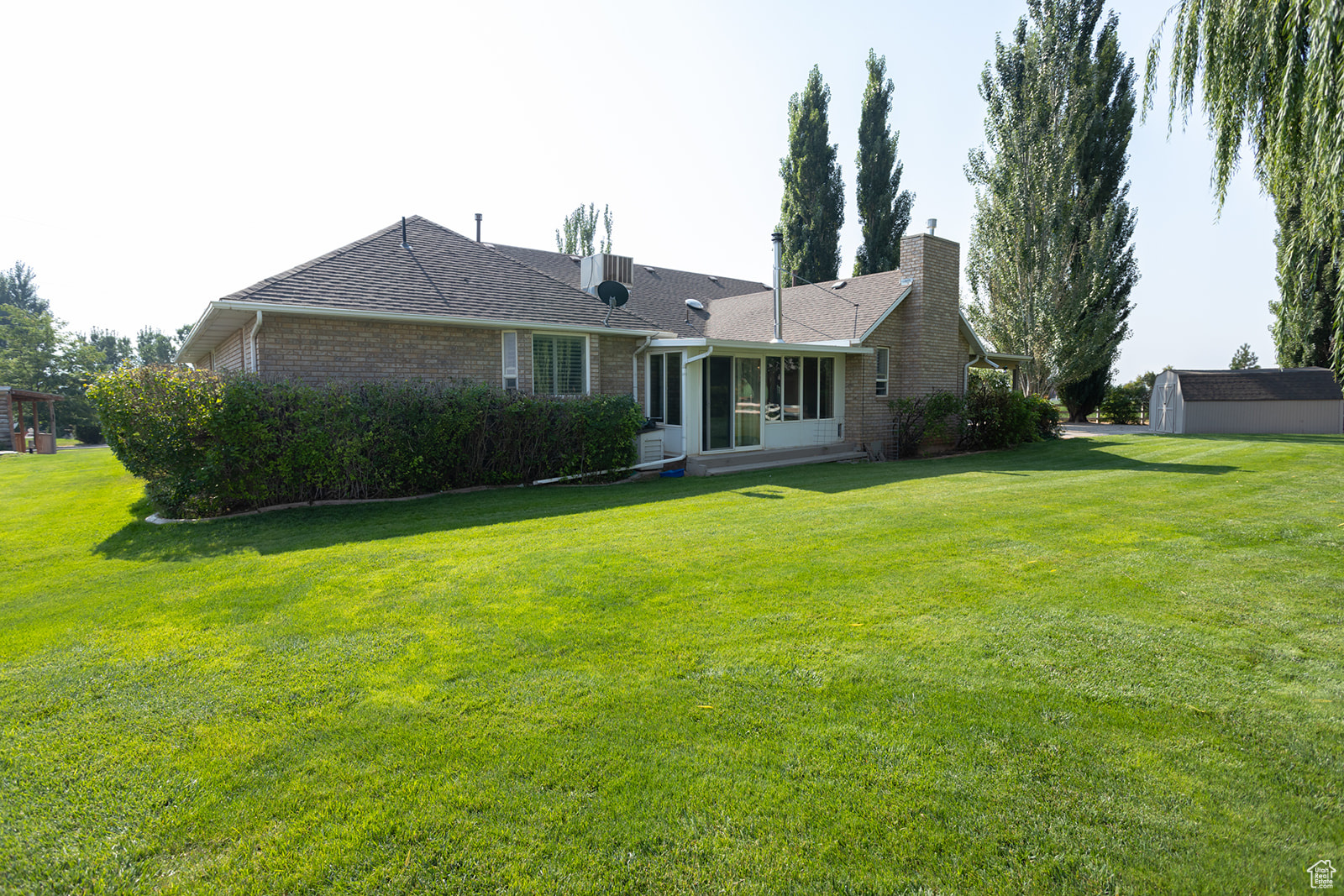 Rear view of property with a yard and a storage unit