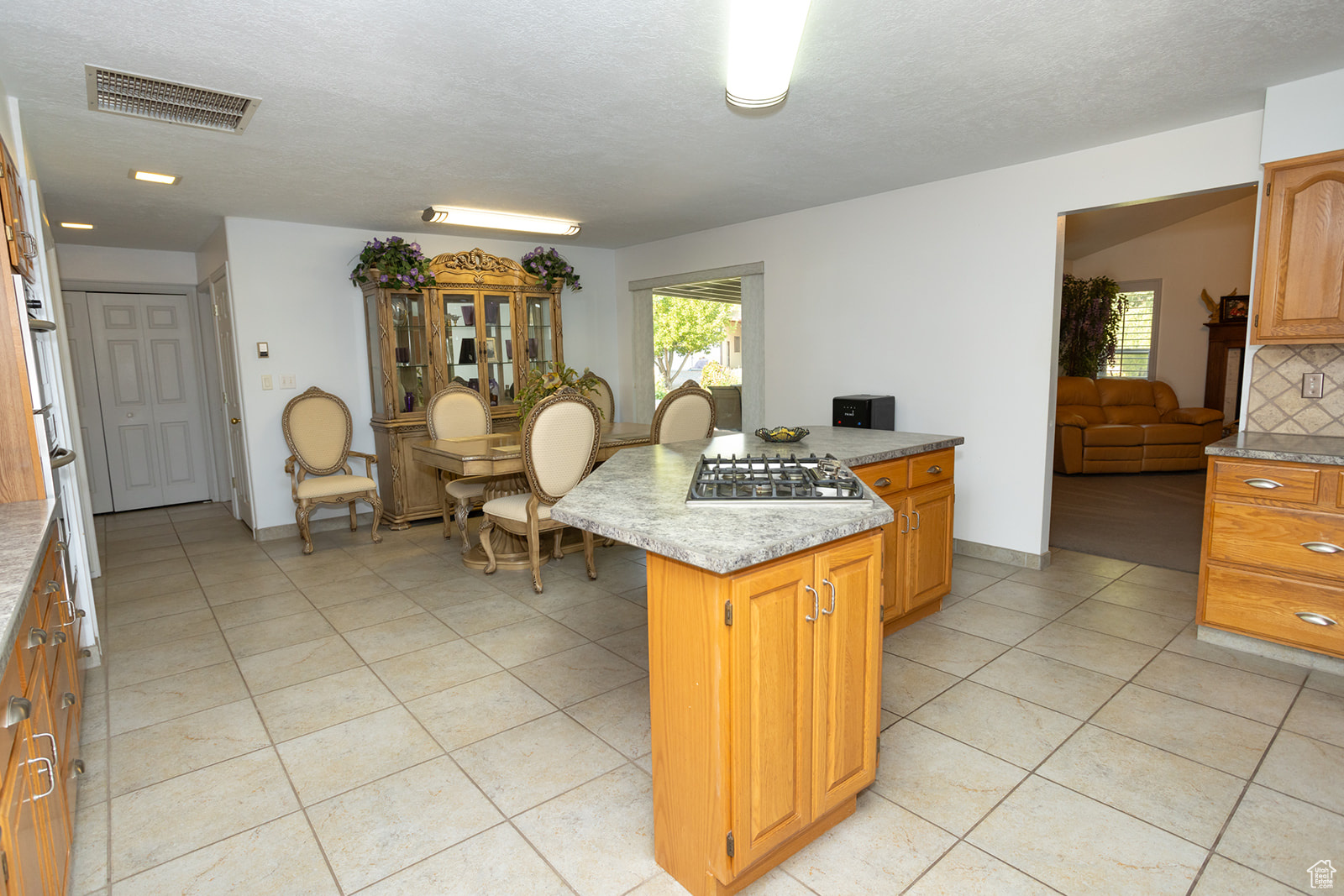 Kitchen featuring light tile patterned floors, a textured ceiling, a center island, and decorative backsplash