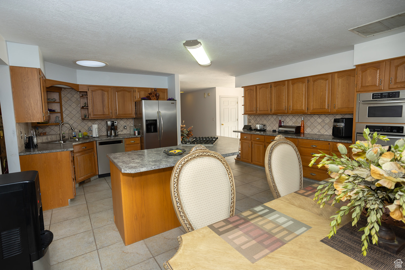 Kitchen featuring appliances with stainless steel finishes, a kitchen island, backsplash, and sink