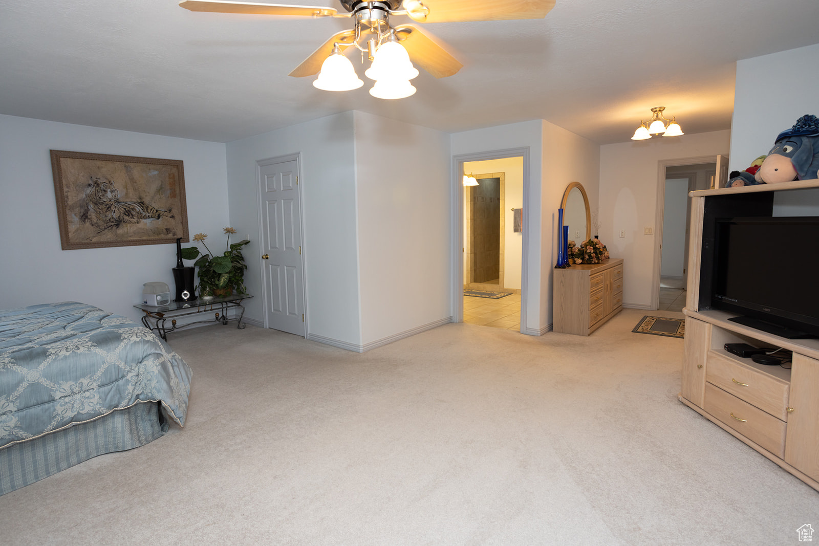 Bedroom with ceiling fan with notable chandelier and light colored carpet