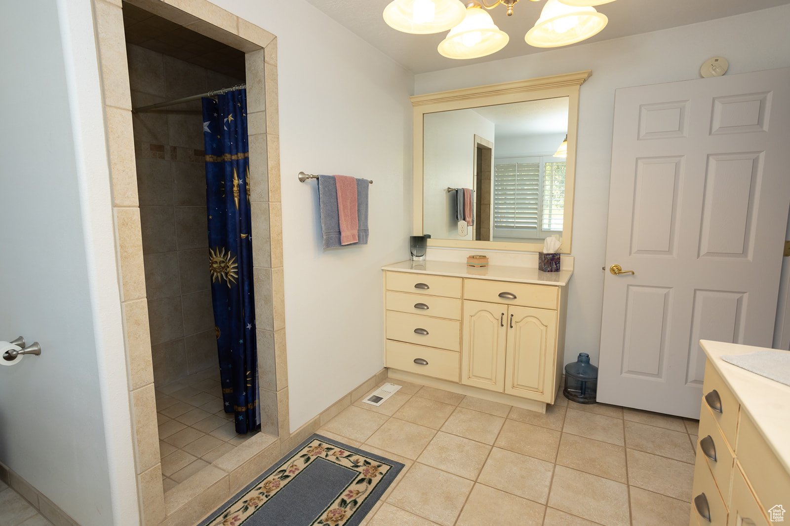 Bathroom with vanity, walk in shower, tile patterned floors, and a chandelier